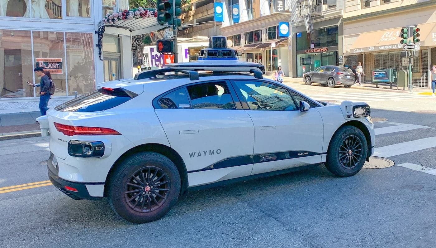 Ilustración de un coche autónomo alejándose con una maleta en el maletero, dejando a un pasajero confundido en la acera.