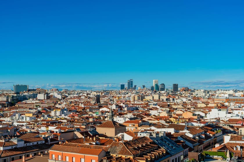 Fotografía de un paisaje urbano desde una ventana, con un móvil en primer plano mostrando una app de mapas, simbolizando