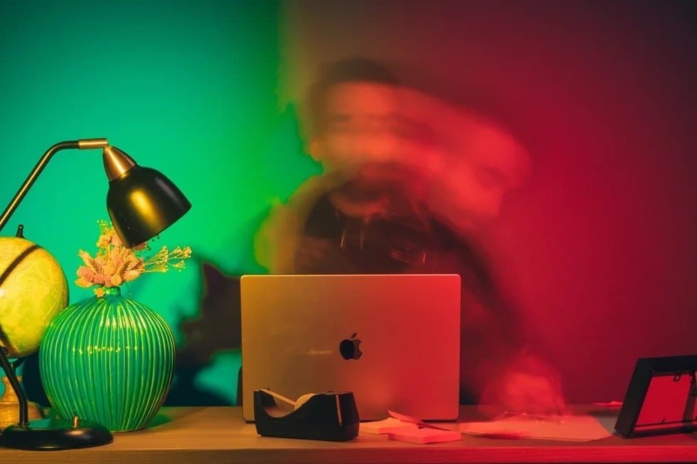 Persona mirando una pantalla con expresion de agotamiento, rodeada de notificaciones borrosas