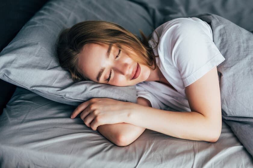 Persona durmiendo plácidamente sin dispositivos electrónicos cerca, en una habitación oscura y ordenada.