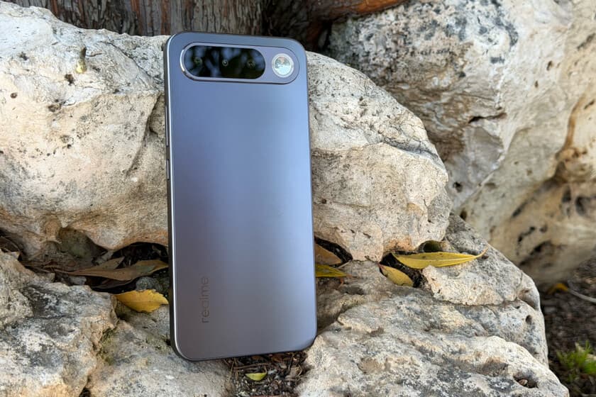 Realme 16 5G ultradelgado sobre una mesa de madera, junto a un reloj analógico y un cuaderno abierto.