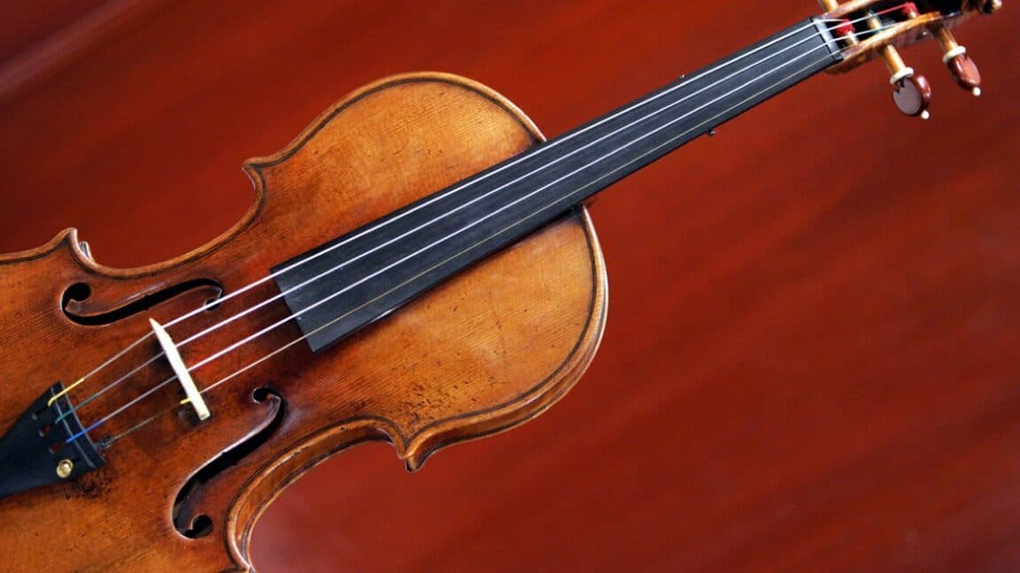 Violín clásico sobre fondo rojo, con una superposición de líneas de simulación digital.