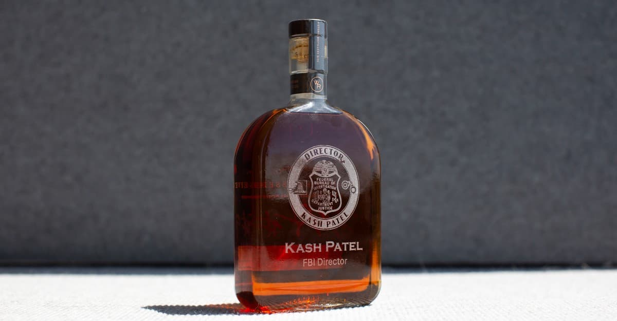 Botella de bourbon Woodford Reserve con grabado 'Kash Patel FBI Director' sobre fondo oscuro