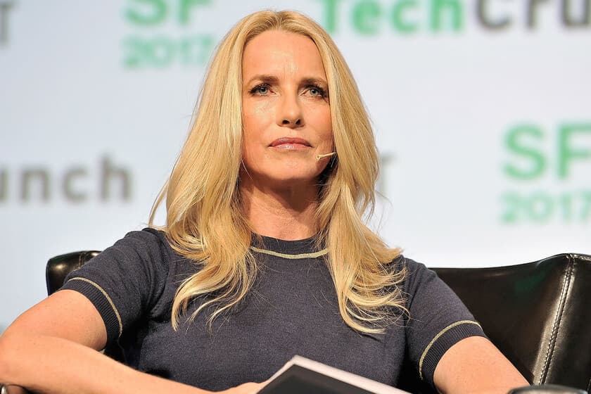 Laurene Powell Jobs en un evento filantrópico, con expresión serena y fondo desenfocado de edificios modernos.