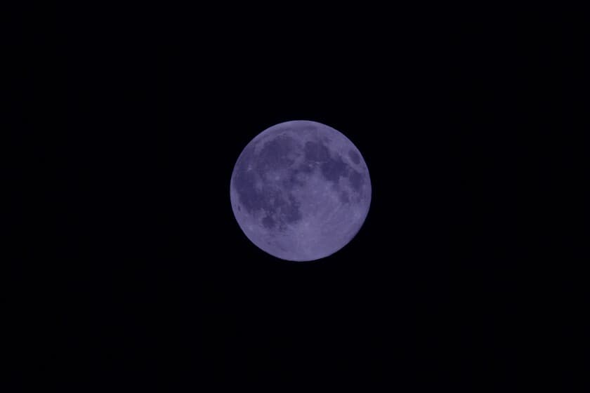 Fotografía de una luna llena brillante en el cielo nocturno, sin filtros azules, con un fondo estrellado.