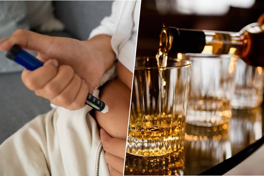 Persona sosteniendo un vaso de agua con una mano y un teléfono con la otra, fondo desenfocado de botellas de alcohol