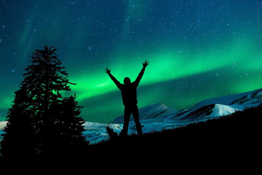 Turistas con smartphones apuntando al cielo nocturno iluminado por auroras boreales en Noruega