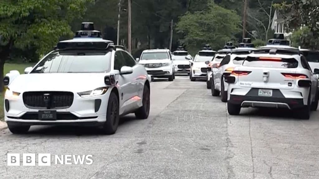 Varios coches Waymo detenidos en una calle residencial de Atlanta, con luces intermitentes y sin conductor visible.