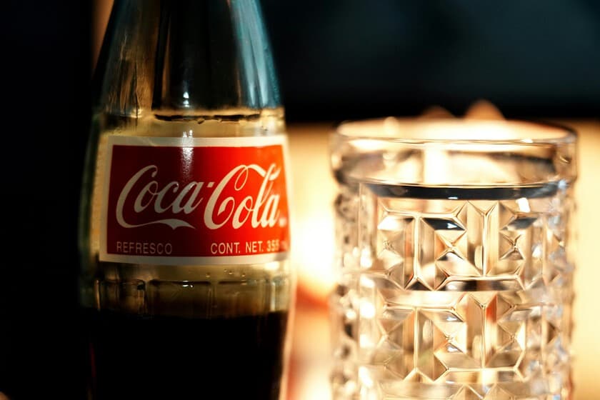 Botella de Coca-Cola clásica junto a una lata de New Coke, con fondo vintage