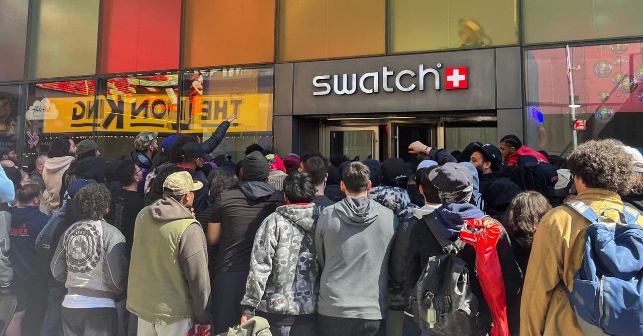 Multitud agolpada frente a una tienda Swatch, con caras de frustración y pancartas de la colección colaboración.