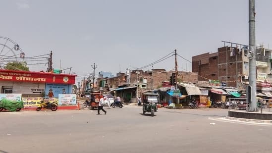 Calle vacía bajo un sol abrasador en Banda, India, con un cartel que indica el cierre a las 10 am.