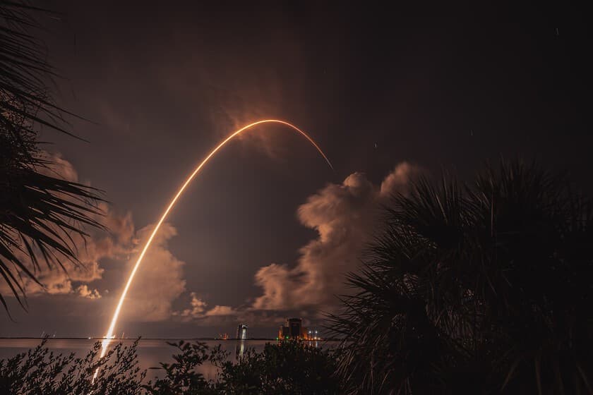 Estela de cohete Falcon 9 sobre un cielo estrellado, con satélites Starlink visibles como puntos brillantes