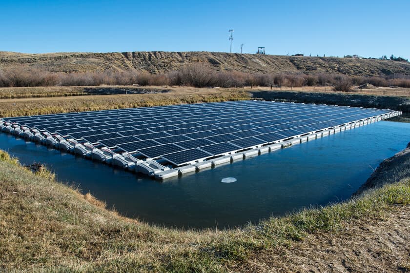 Paneles solares flotantes en un embalse con montañas al fondo