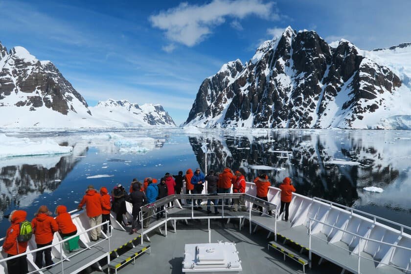 Crucero navegando entre icebergs en la Antártida con turistas en cubierta