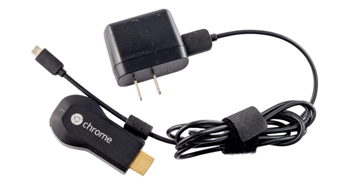 Un Chromecast de primera generación desconectado, con luz apagada, sobre una mesa de madera