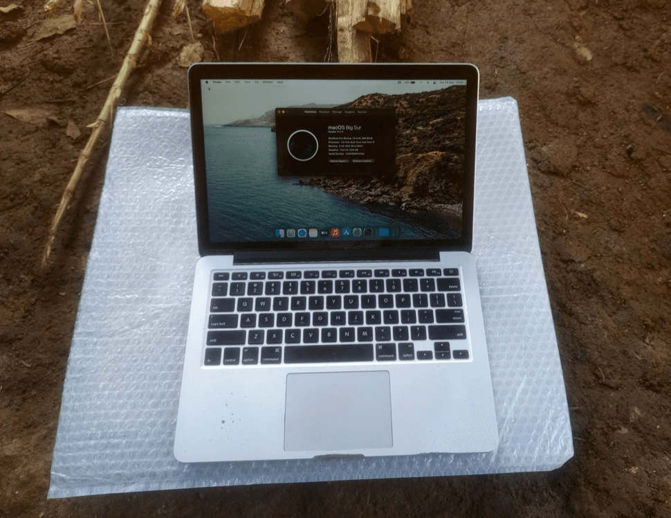 Laptop en una mochila junto a un paisaje rural de Uganda