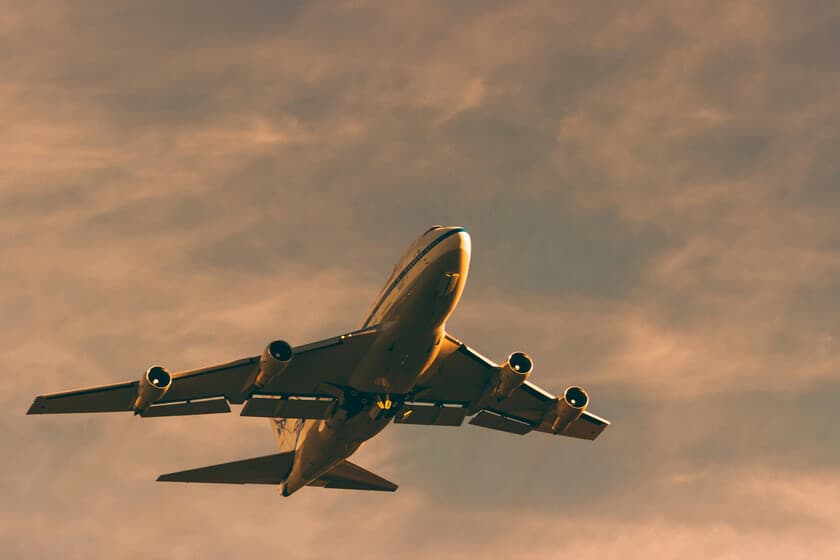 Refinería de petróleo al atardecer con aviones de pasajeros volando sobre ella