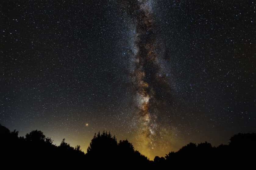 Fotografía nocturna de la Vía Láctea sobre un paisaje urbano oscurecido, con el horizonte de Los Ángeles de fondo.
