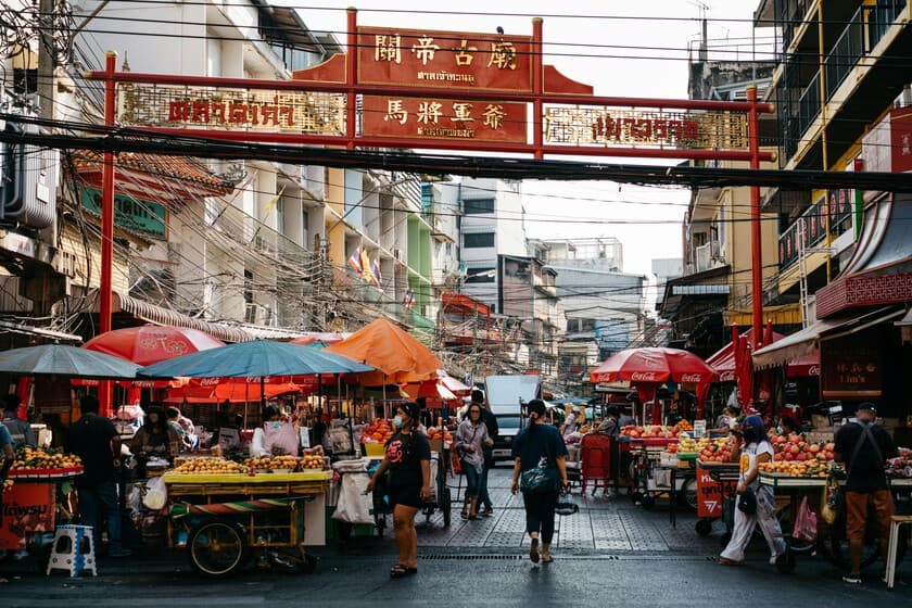 Calle comercial con letreros en chino y japonés, peatones asiáticos variados