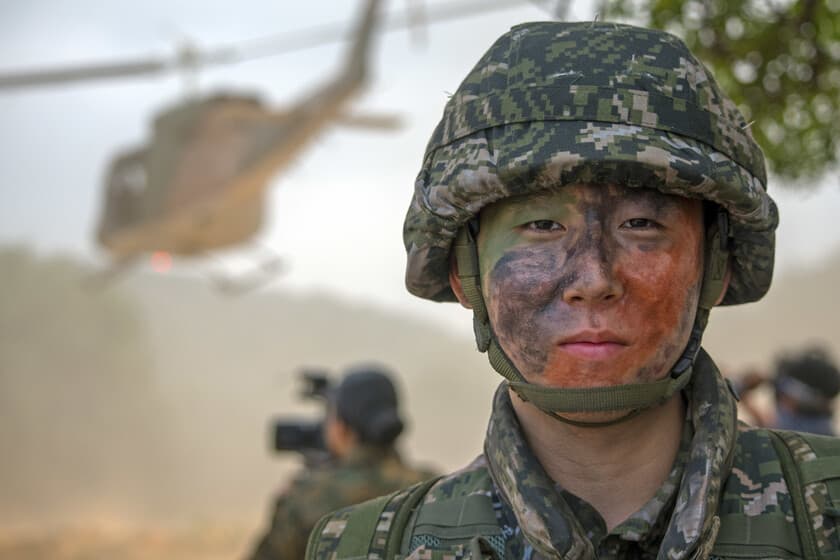 Soldado surcoreano con uniforme militar frente a un espejo, mostrando cambios faciales sutiles