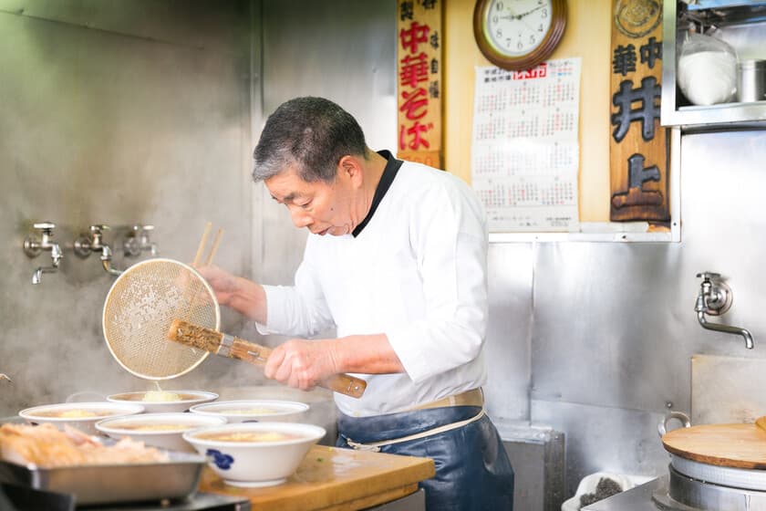 Un cuenco de ramen humeante sobre una encimera de madera, con un cartel de 'Cerrado' al fondo