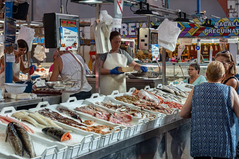 Bandeja de poliespán con filetes de pescado envueltos en plástico, sobre fondo de supermercado