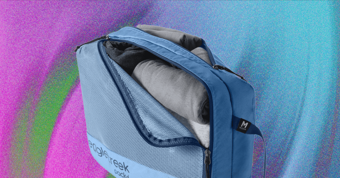 Cubos de viaje organizados dentro de una maleta abierta, con ropa doblada y accesorios