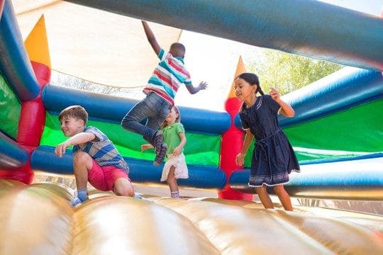 Personas saltando en un castillo inflable en una oficina, simbolizando trabajo autogestionado y diversión