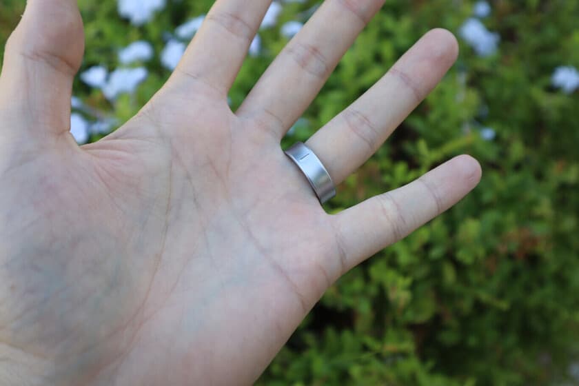 Anillo inteligente en un dedo con fondo de termómetro al sol