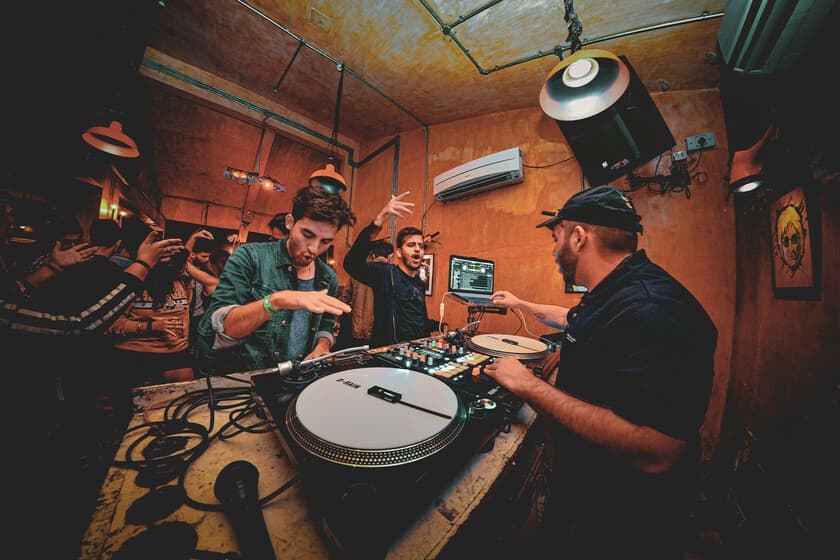 Interior de un listening bar con vinilos, altavoces vintage y clientes sentados en silencio escuchando música