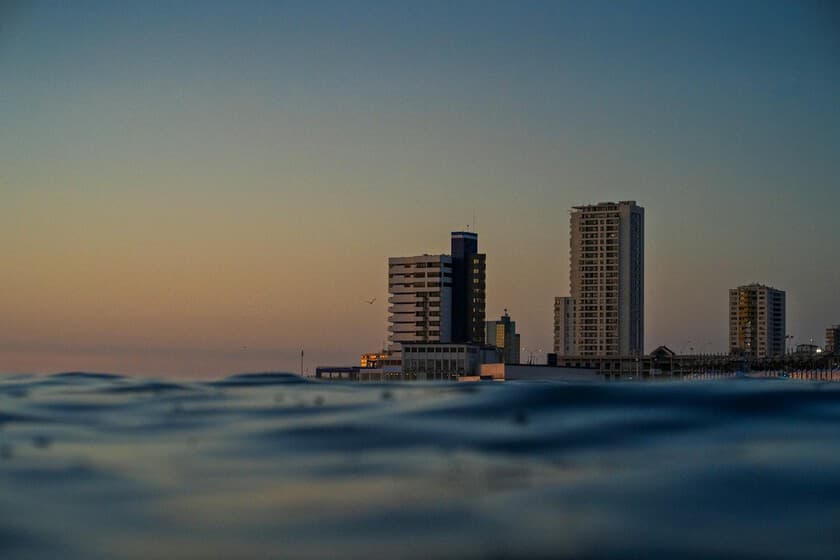 Persona caminando por una playa al atardecer, con el mar de fondo