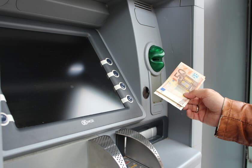 Billetes de euro y monedas sobre una mesa de madera junto a una cartera