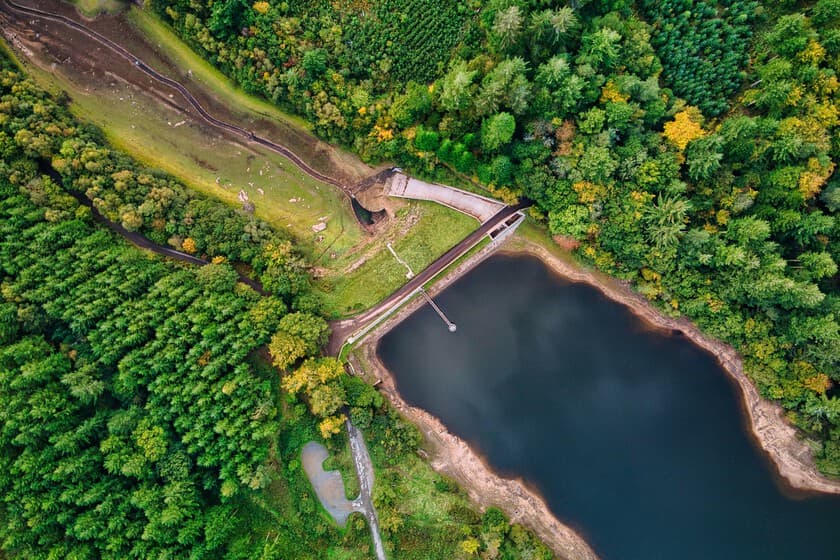 Fotografía de una presa siendo demolida con maquinaria pesada, río al fondo fluyendo libremente