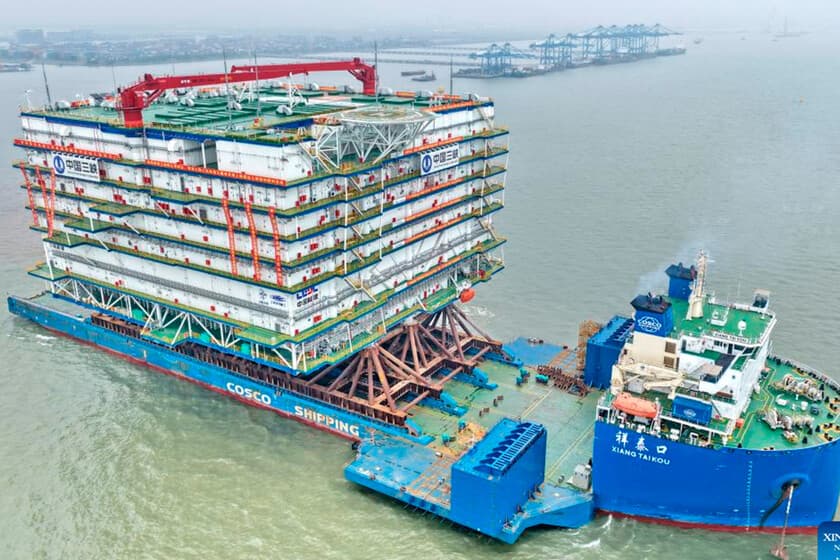 Plataforma metálica gigante en el mar, con módulos de conversión de energía, rodeada de turbinas eólicas marinas.
