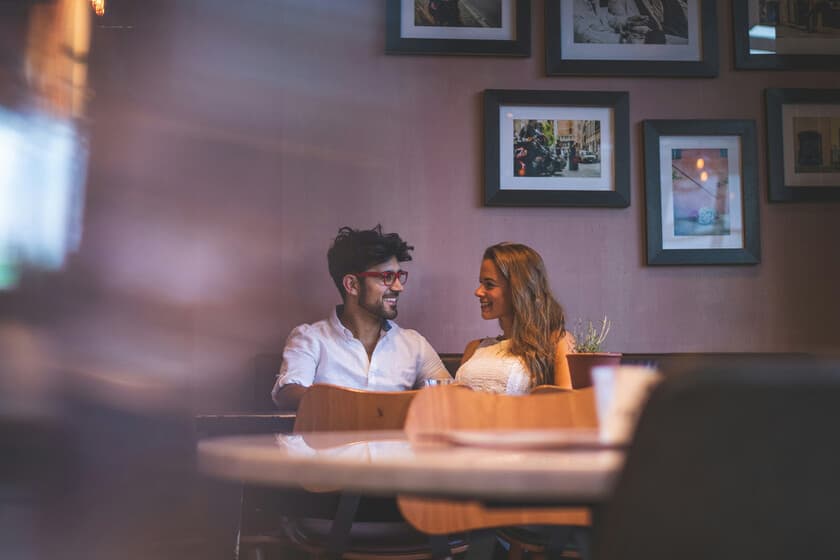 Persona joven sonriendo sola en un café con un libro, sin mirar el móvil, simbolizando el solo-maxxing y la desconexión