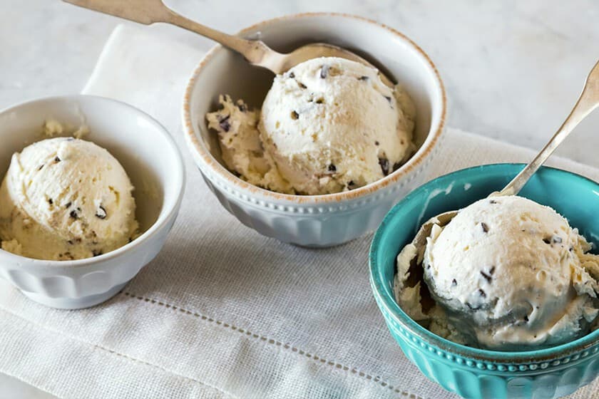 Heladera compacta de color blanco sobre encimera de cocina pequeña, con recipiente de helado de fresa al lado