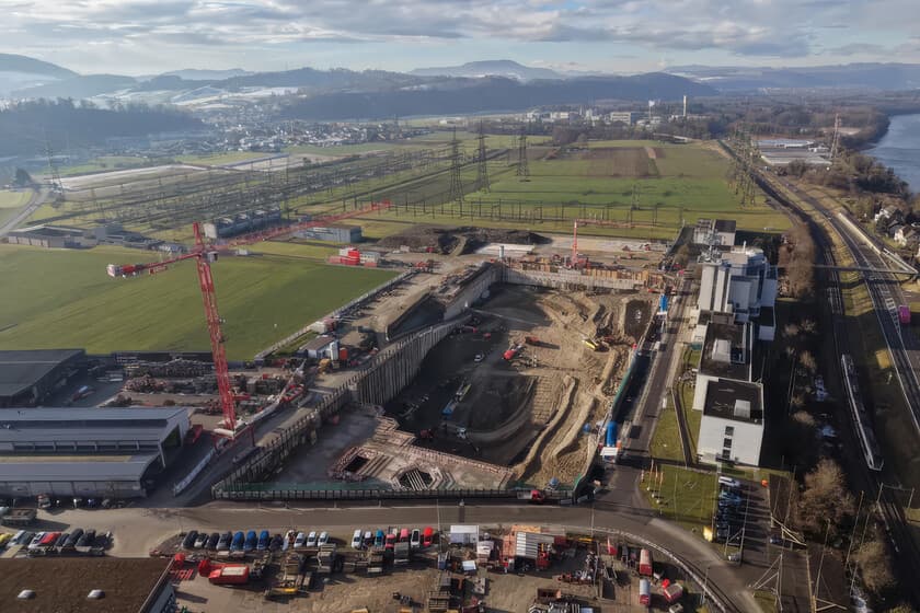 Vista aérea de la excavación del foso en Suiza para la batería de gravedad, con maquinaria pesada y el paisaje alpino de