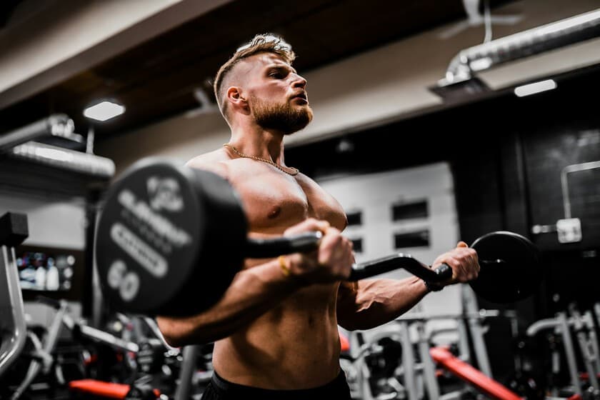 Persona realizando curl de bíceps con mancuerna en un gimnasio minimalista