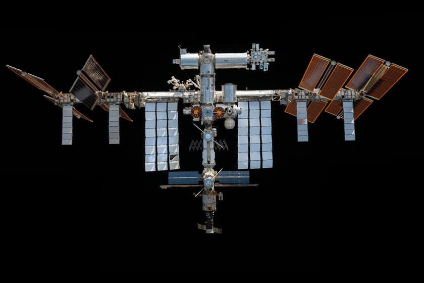 Astronautas de la ISS en trajes espaciales dirigiéndose a las naves Soyuz atracadas, con la Tierra de fondo