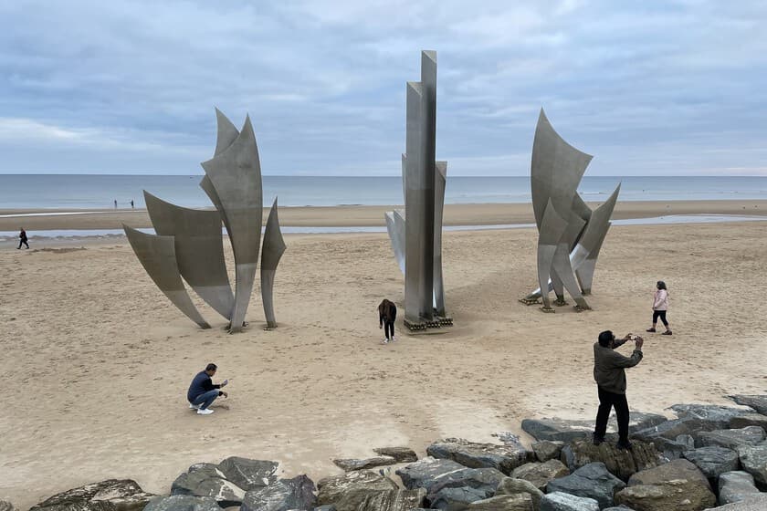 Primer plano de arena de playa con fragmentos metálicos visibles, tonos grises y marrones, luz natural