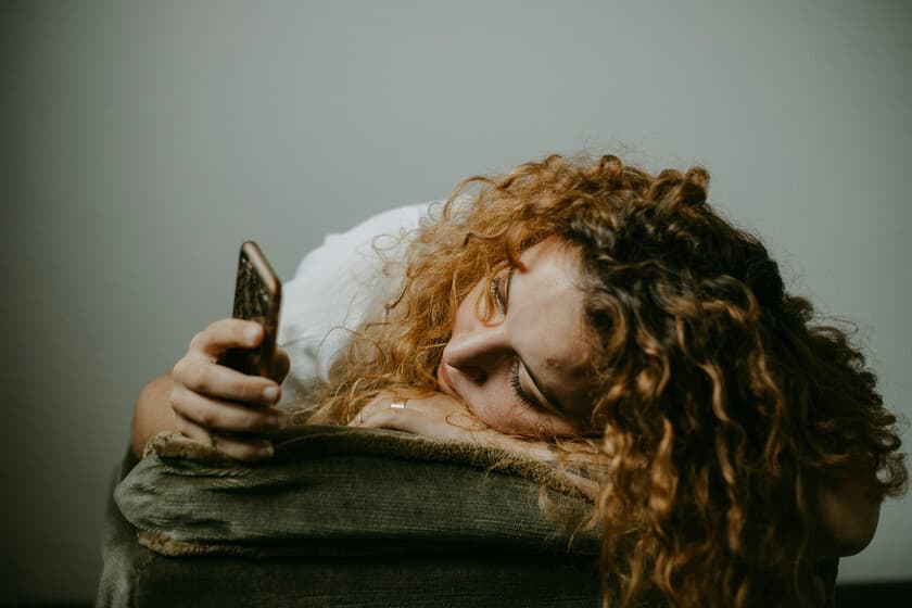 Persona mirando el reloj en la cama un domingo por la tarde, expresión de angustia