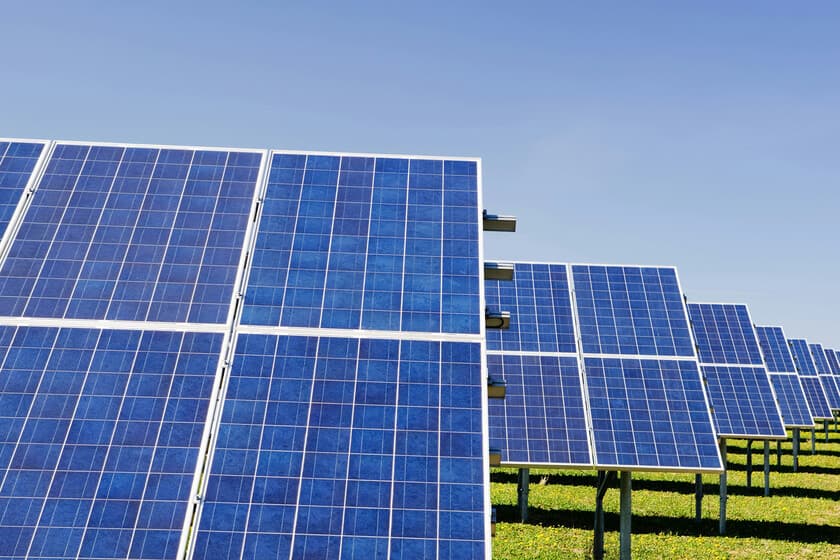 Paneles solares en un campo español al atardecer, con líneas de alta tensión al fondo