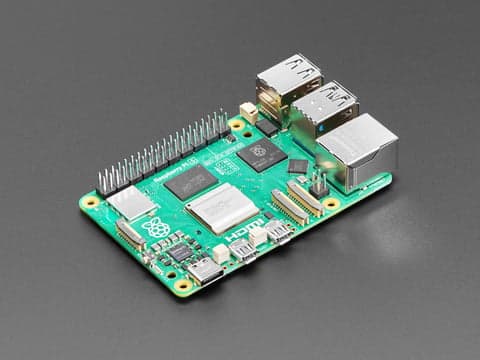 Raspberry Pi 5 sobre una mesa de madera con cables conectados, fondo desenfocado