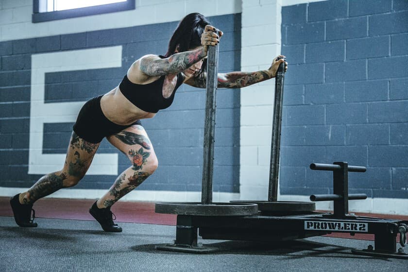 Persona haciendo un burpee con pesas rusas al lado de una cinta de correr