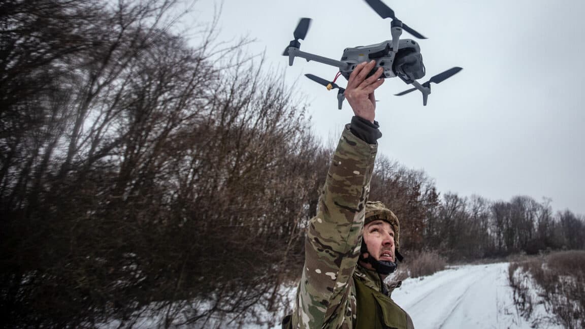 Dron militar sobrevolando un campo de batalla al atardecer