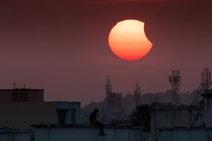 Astrónoma mirando al cielo con un telescopio durante un eclipse solar