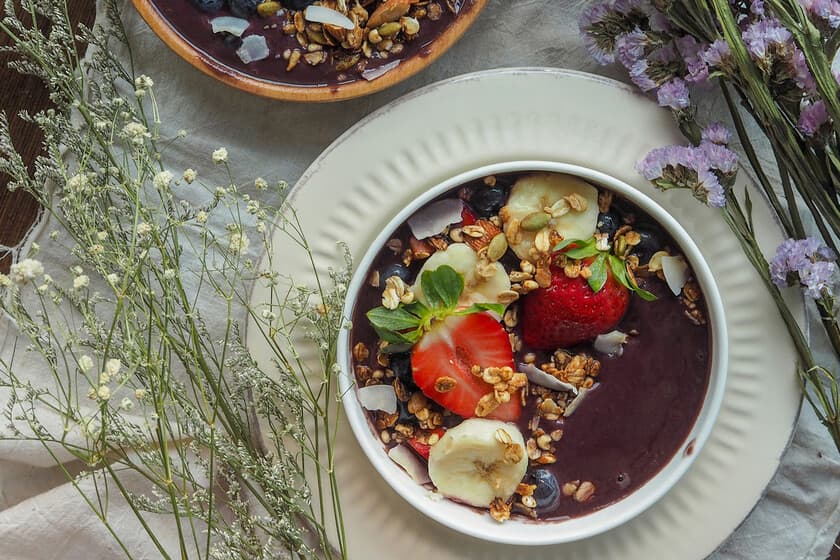 Bol de açaí con granola y frutas sobre fondo claro
