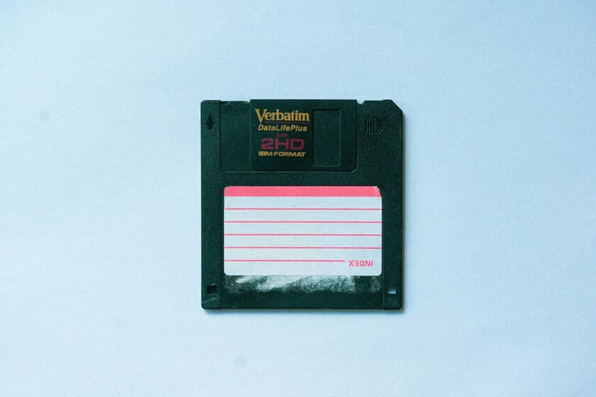 Disquete de 3,5 pulgadas junto a un ordenador moderno, simbolizando minimalismo digital