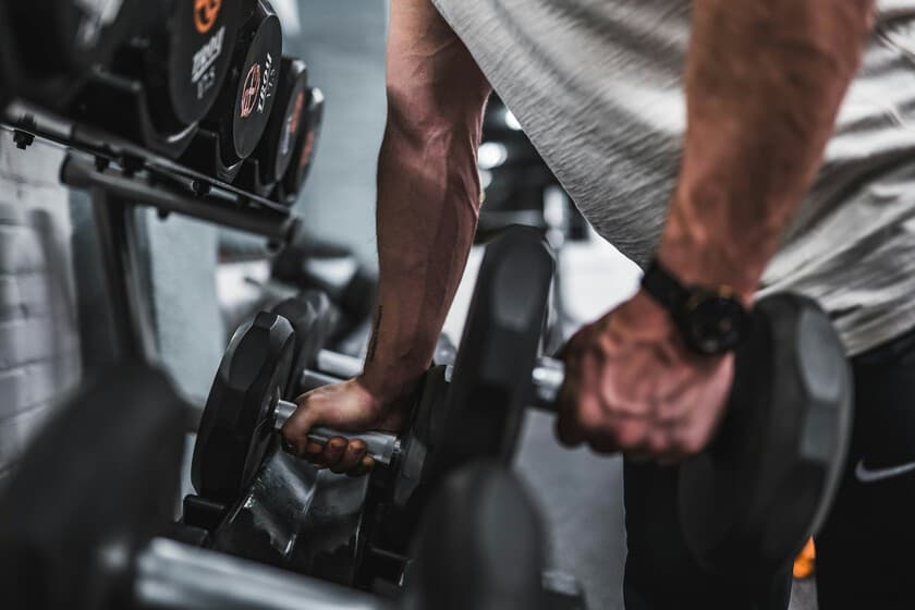 Persona levantando pesas en un gimnasio minimalista con luz natural