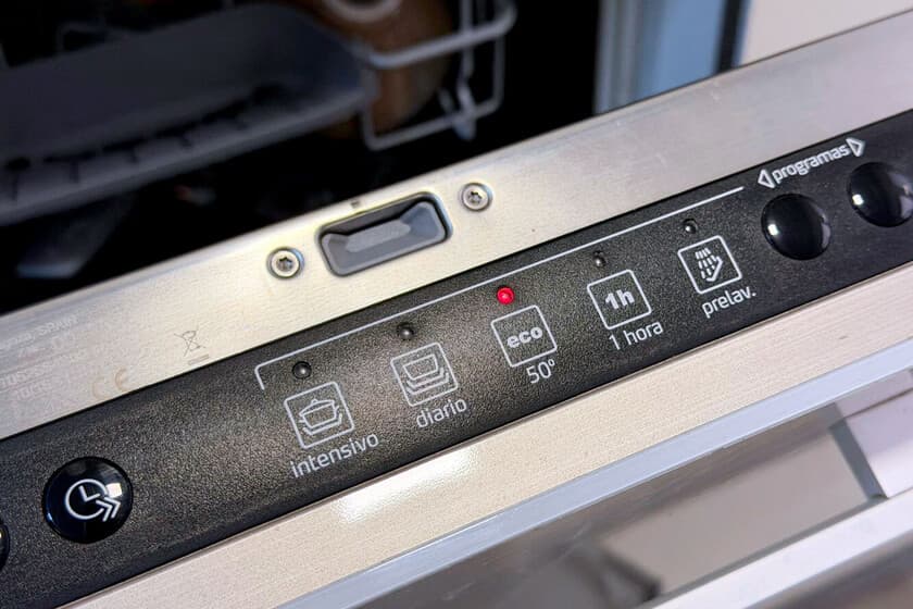 Lavavajillas abierto con platos sucios, modo eco seleccionado en el panel